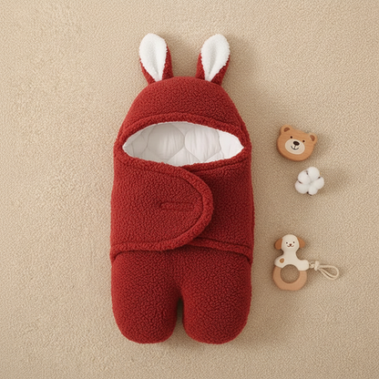 Baby sleeping bag in red knit with bunny ears and wooden toy accessories